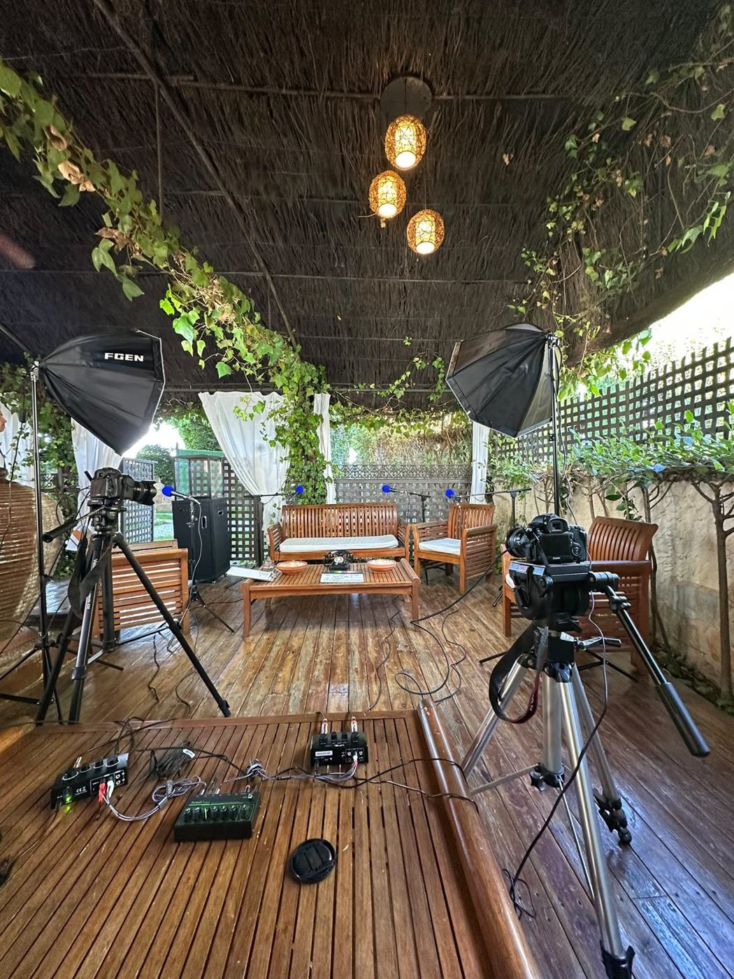 Vista del set bajo la pérgola con las lámparas encendidas y la hiedra